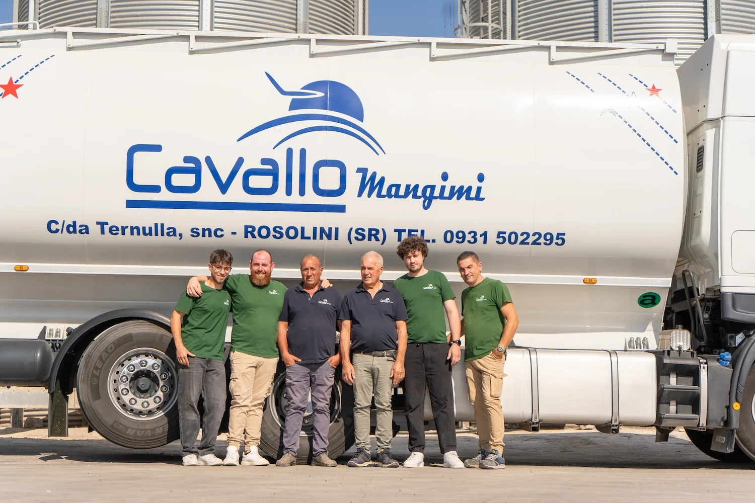 Foto di parte dello staff all'esterno dell'azienda con camion nello sfondo